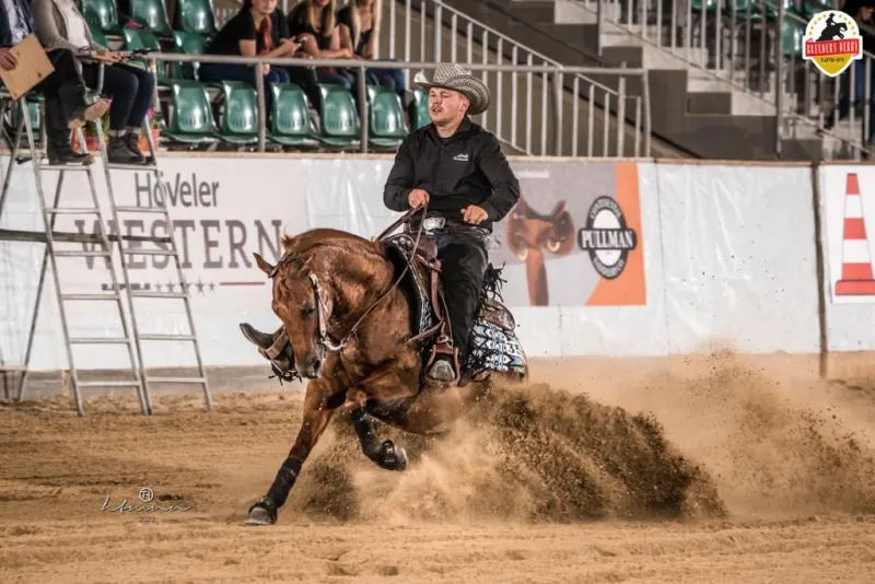 Westernreiter beim Sliding Stop in einer Reithalle